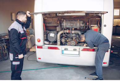 photo of two men doing maintenance on a bus