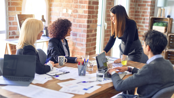Diverse Group of Four Adults work together in a meeting room in an office