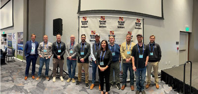 11 new licensed land surveyors stand in front of a maryland society of surveyors sign at conference