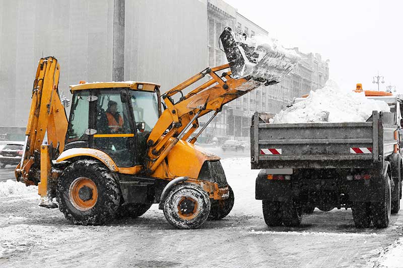 snow plow dumps snow collected into a snow collection truck